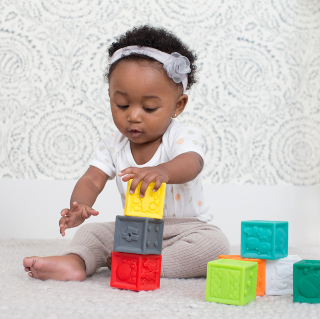 A young child playing with blocks from an activity kit for early childhood development.